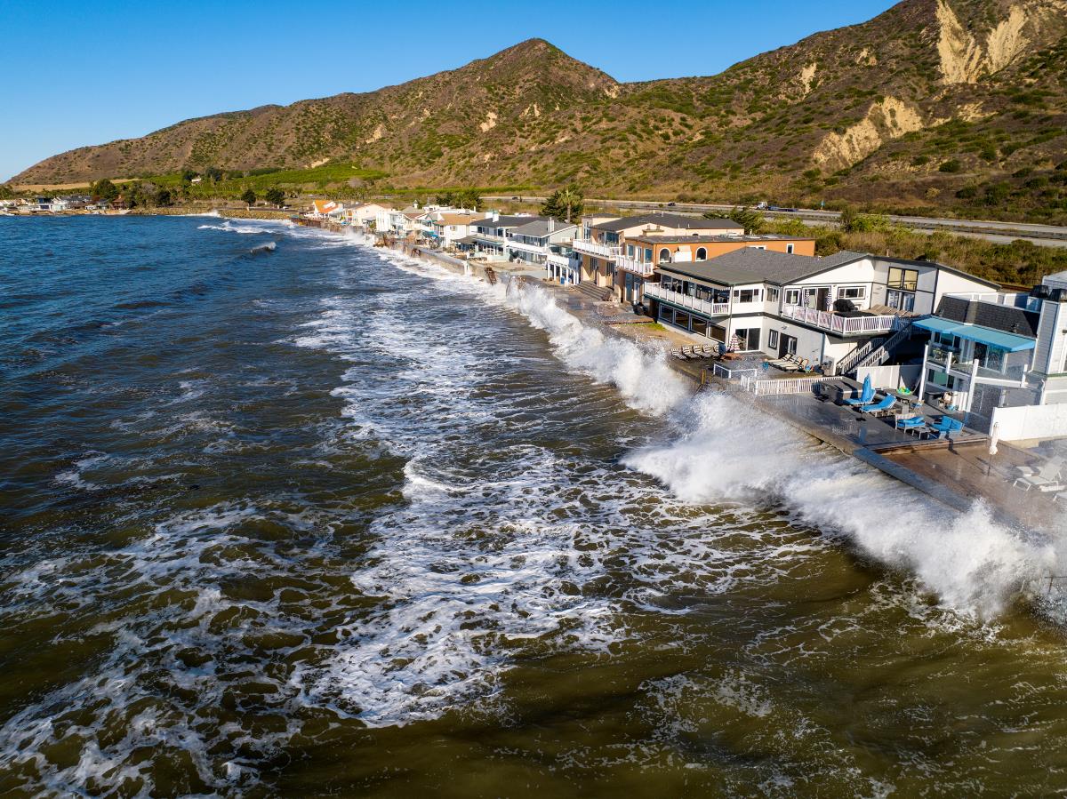 Documentary aerial photograph of Mondos Cove Beach during a king tide, with waves along the coastal houses